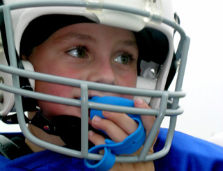 youth football player in helmet and uniform pads